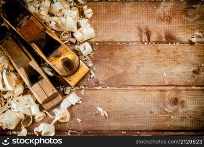 Working tool. Planer with wooden shavings. On a wooden background. High quality photo. Working tool. Planer with wooden shavings.