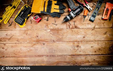 Working tool. Screwdriver with self-tapping screws on the table. On a wooden background. High quality photo. Working tool. Screwdriver with self-tapping screws on the table.