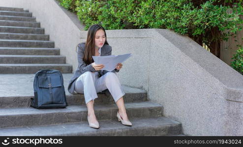 Working woman concept a woman sitting on the step looking at the job applications with feeling anxious and desperate.