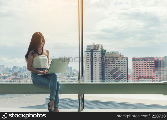 working women white shirt blue jean clothe black long hair sitting use computer laptop