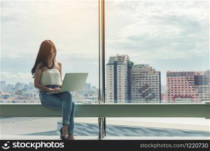 working women white shirt blue jean clothe black long hair sitting use computer laptop
