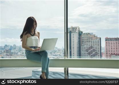 working women white shirt blue jean clothe black long hair sitting use computer laptop