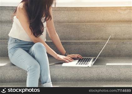working women white shirt blue jean clothe black long hair use computer laptop sitting on stair