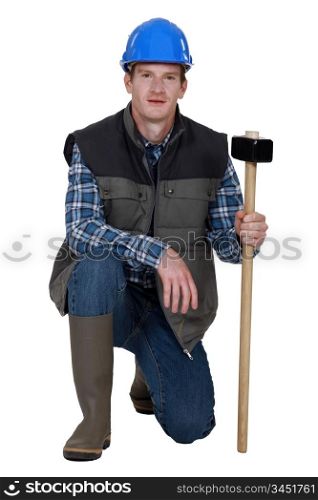 Workman crouching with hammer in hand