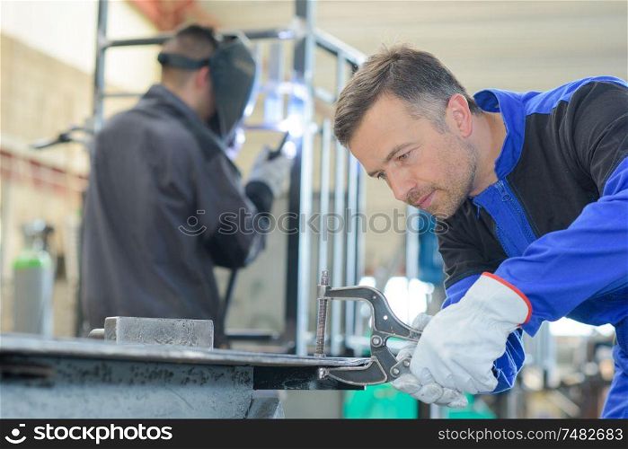 Workman fixing clamp onto bench