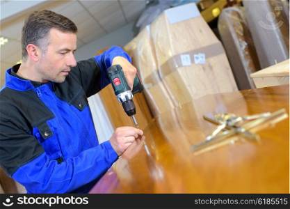 Workman fixing screw into lid of coffin