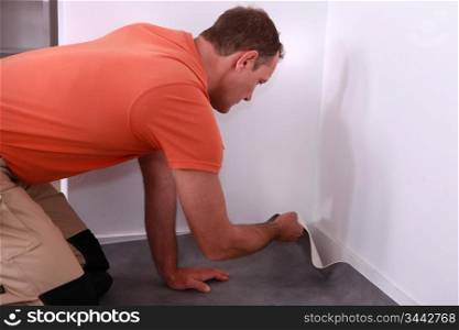 Workman putting down linoleum flooring