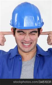 workman putting fingers in his ears to block out noise