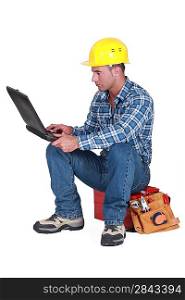 Workman sitting on a toolbox with notebook