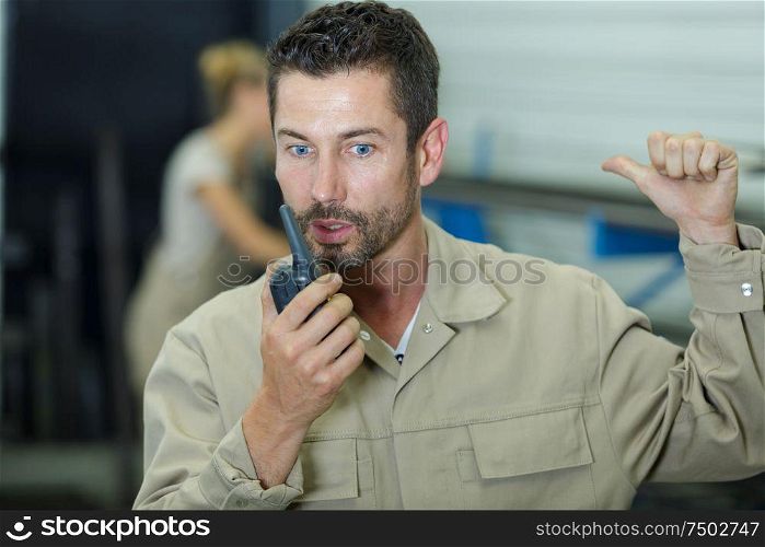 workman talking into walkie-talkie with urgent message
