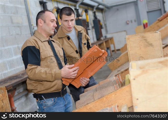 workmen in discussion holding roof tile