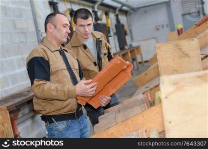 workmen in discussion holding roof tile