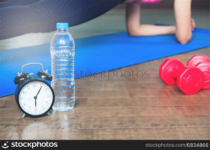 Workout and Healthy Lifestyle concept, Alarm clock, bottle of water and sport equipment, Yoga at home