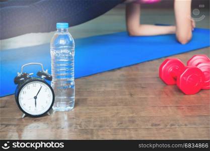 Workout and Healthy Lifestyle concept, Alarm clock, bottle of water and sport equipment, Yoga at home