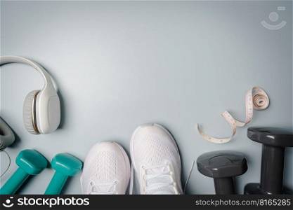 Workout flat-lay with sneakers, dumbbell, and headphones on gray background top view. Sport and fitness concept. Workout flat-lay with sneakers