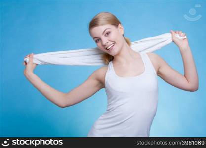 Workout, hygiene concept. Smiling woman holding a towel around her shoulders smiling at the camera, studio shot on blue background. Woman with a towel around her shoulders smiling