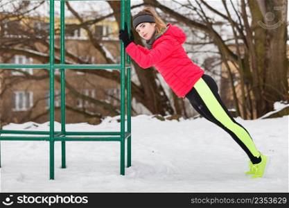 Workout in public park. Woman wearing warm sportswear urban street training exercising outside during winter.. Woman urban exercising outside during winter
