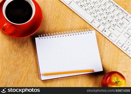 Workplace. Cup of coffee notepad and keyboard on wooden table