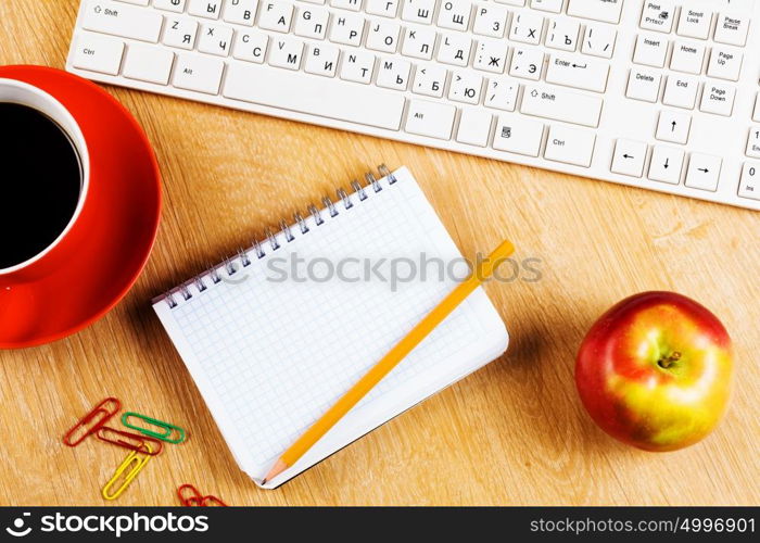 Workplace. Cup of coffee notepad and keyboard on wooden table