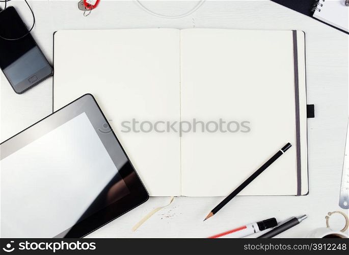 Workplace. Empty notepad, tablet pc and smart phone on white wooden table