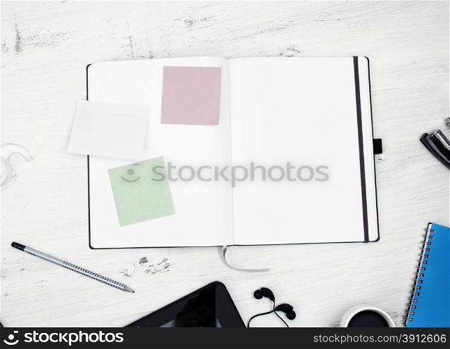 Workplace. Empty notepad with stickers, tablet pc and coffee on white wooden table