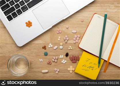 Workplace laptop pc and pills. Colorful pills and laptop pc on the workplace