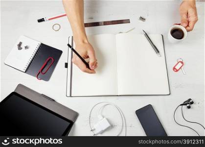 Workplace. Man working on notepad, tablet pc and smart phone on white wooden table