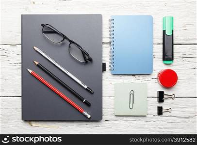 Workplace. White wooden table with notepad, colorful pencils and supplies.