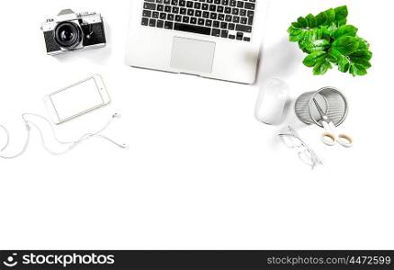 Workplace with laptop, phone, notebook, photo camera, green plant. Office desk white background. Hero header