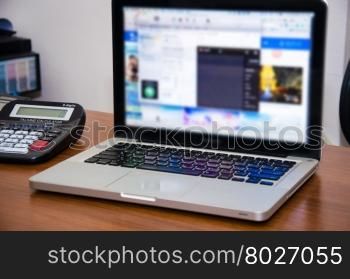 Workplace with open laptop with black screen on modern wooden desk, angled notebook on table in home interior, filtered image, cross process
