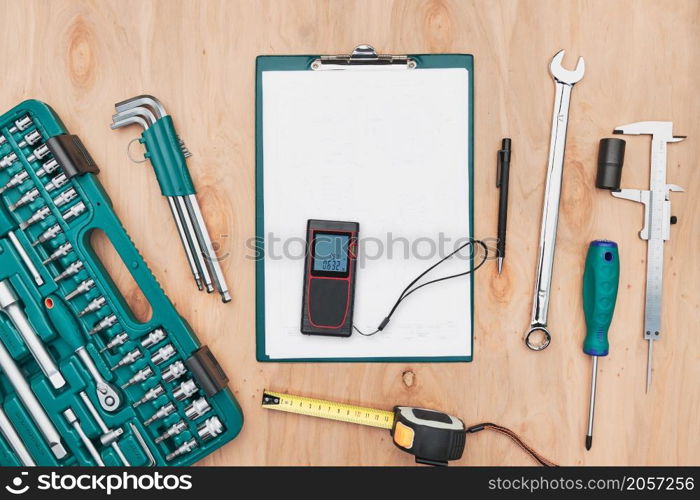 Workshop table with many tools. Wrench, spanner, calliper and ratchet with many attachments. Clipboard with white paper. Work tools. Universal tool set. Professional equipment. Background. Copy space