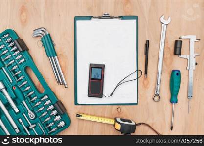 Workshop table with many tools. Wrench, spanner, calliper and ratchet with many attachments. Clipboard with white paper. Work tools. Universal tool set. Professional equipment. Background. Copy space