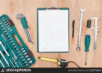 Workshop table with many tools. Wrench, spanner, calliper and ratchet with many attachments. Clipboard with white paper. Work tools. Universal tool set. Professional equipment. Background. Copy space
