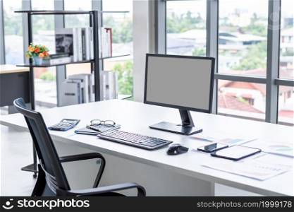Workspace Business mockup desktop computer empty black gray screen with keyboard notebook and other accessories on Modern dark wooden office corner and black office chairs with window in office