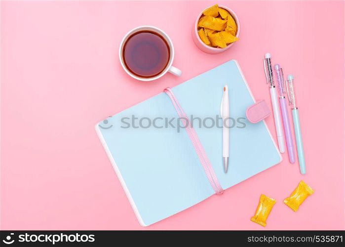 workspace desk styled design office supplies, hot tea and candy on pink pastel background minimal style