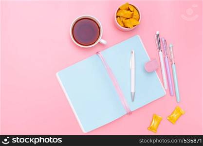 workspace desk styled design office supplies, hot tea and candy on pink pastel background minimal style