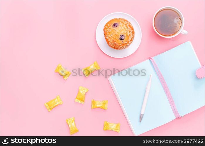 workspace desk styled design office supplies, hot tea, candy and cake on pink pastel background minimal style