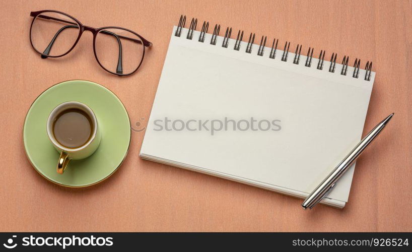 workspace flat lay with blank spiral notebook, pen coffee and reading glasses, long banner format