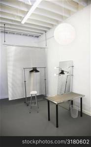 Workspace with table, chair, mirror, clothing rack and room divider.