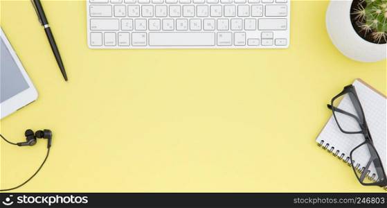 workspace with tablet, keyboard, coffee cup and eyeglasses copy space on yelow background. Top view.