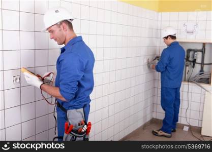 Workteam installing electrics in a tiled room