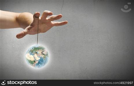 World balance. Close up of human hand and items hanging on fingers. Elements of this image are furnished by NASA