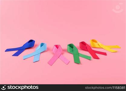 World cancer day (February 4). colorful awareness ribbons; blue, red, green, pink and yellow color on wooden background for supporting people living and illness. Healthcare and medicine concept