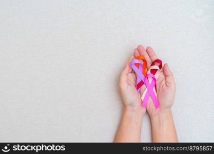 World cancer day, February 4. Hand holding burgundy, oran≥,πnk, peach and purp≤ribbons for supporting peop≤living and ill≠ss. Hea<hcare and medical concept