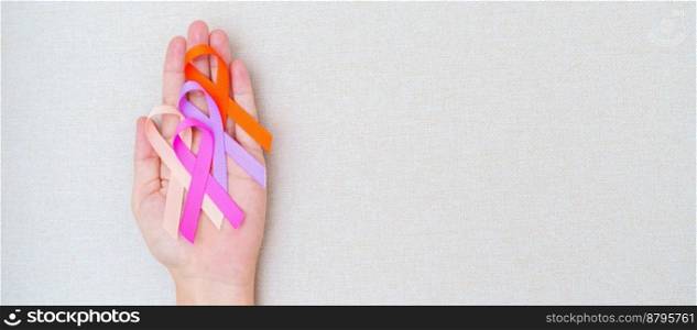 World cancer day, February 4. Hand holding orange, pink, peach and purple ribbons for supporting people living and illness. Healthcare and medical concept