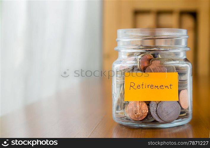 World coins in glass savings jar with retirement plan label