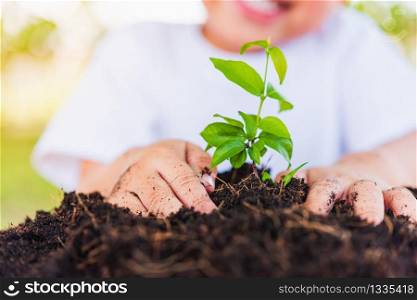 World Environment Day Environment and Save World Concept, Hand of Asian cute cheerful little child boy planting young tree on black soil on green garden background