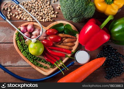 World food day, Top view of various fresh organic fruit and vegetable in heart plate and doctor stethoscope with copy space, studio shot on wooden table, Healthy vegetarian food concept