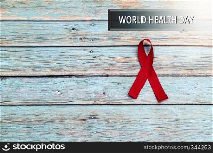 World health day, healthcare and medical concept, red ribbon on the blue wooden background