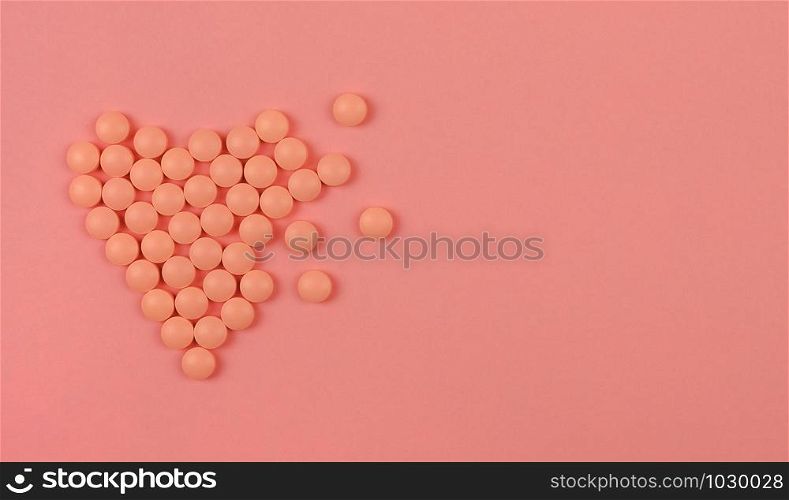 World Heart Day concept. Medical background. Pink Pills in form of heart on pink background. Flat lay. Heart health concept. Copy space.. World Heart Day concept. Medical background. Pink Pills in form of heart on pink background.